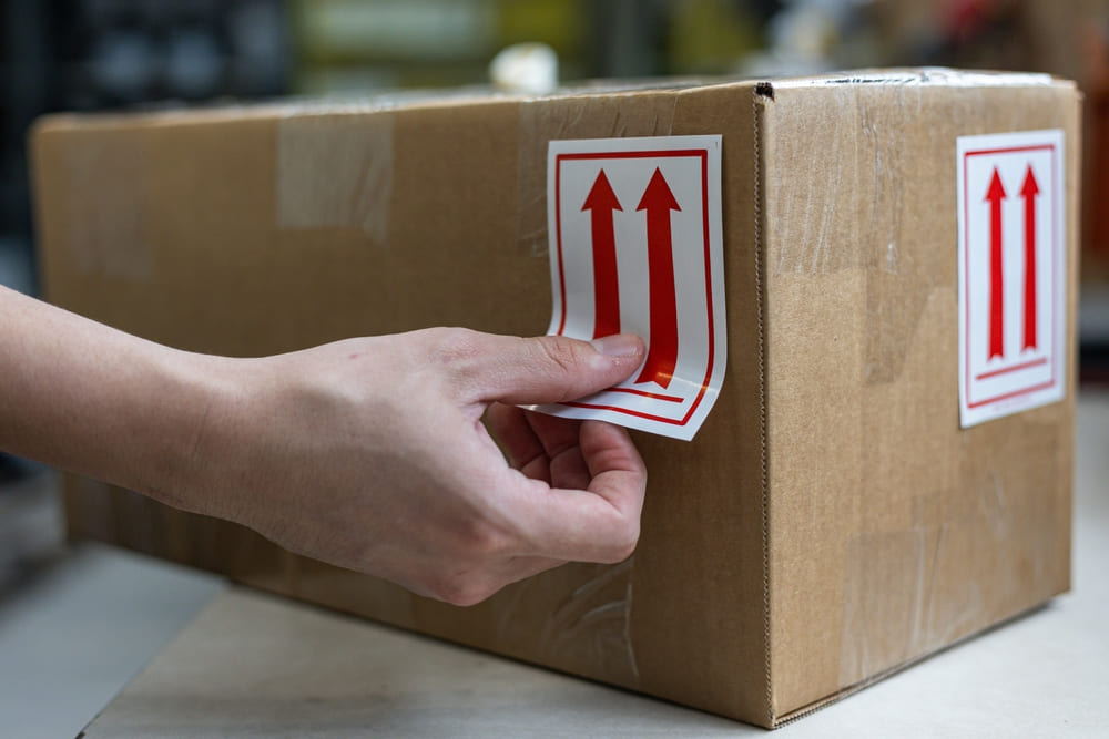persoana lipeste eticheta autoadeziva pe cutie carton
